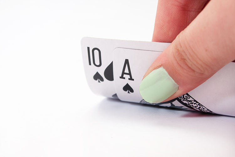 Woman with painted nails holds playing cards on white surface | The Dating Divas