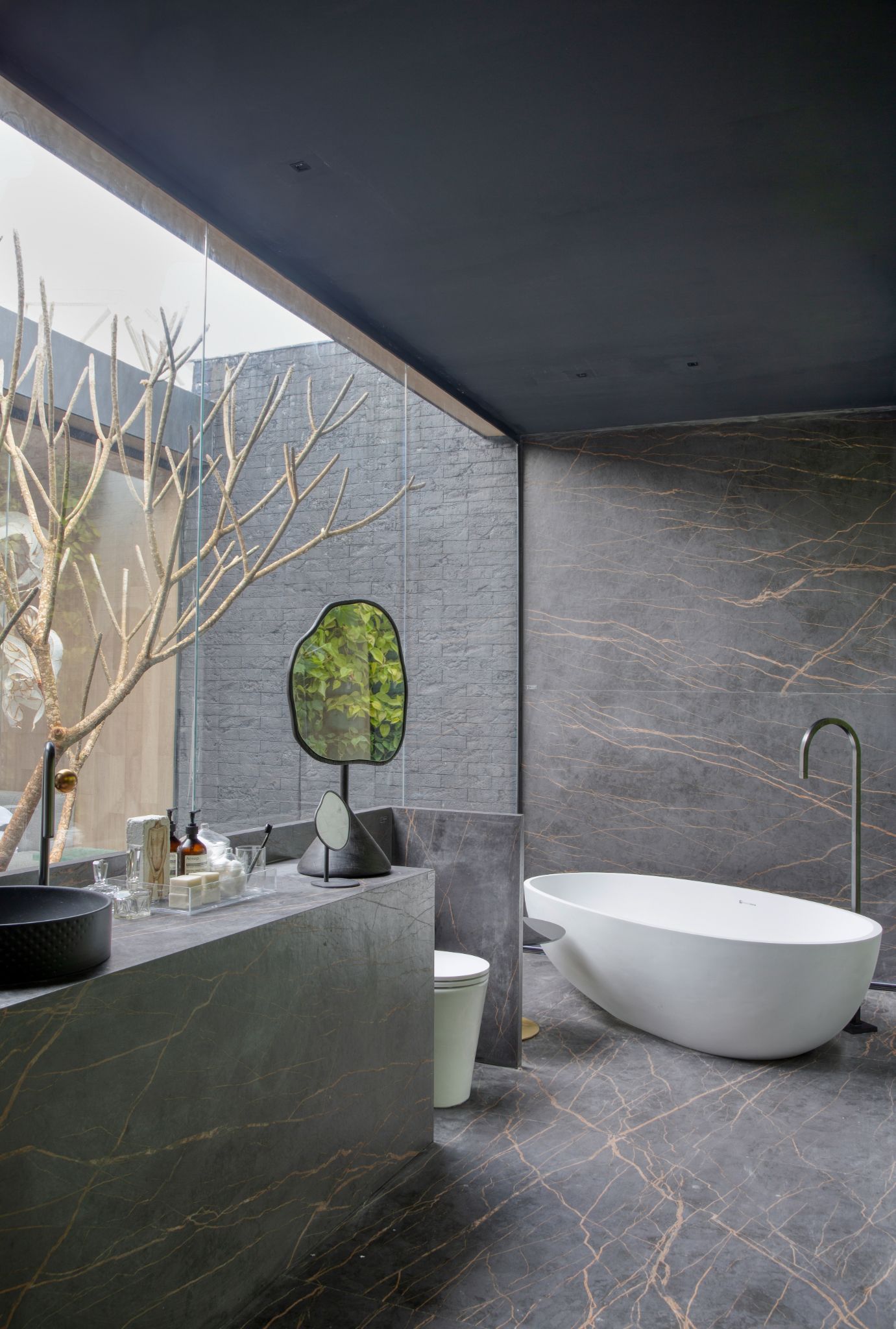 Banheiro com porcelanato cinza revestindo paredes, piso e bancada pia, banheira de imersão branca