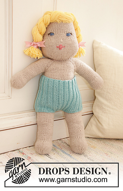 large knit baby doll standing against wall