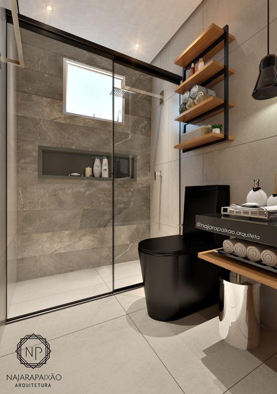 Banheiro com louças pretas, revestimento cinza na parede do box, demais paredes e piso em tons neutros e prateleiras de madeira