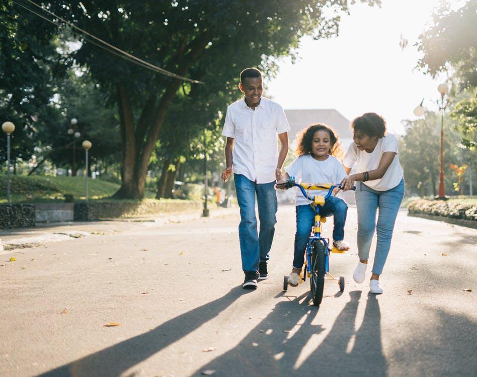 Free Man Standing Beside His Wife Teaching Their Child How to Ride Bicycle Stock Photo