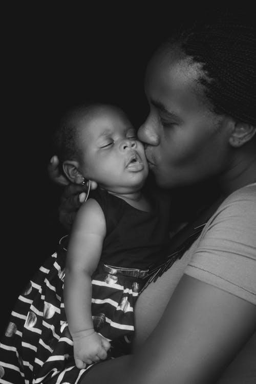 Grayscale Photo of Woman Kissing Child