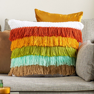 crochet pillow with rows of different color fringe