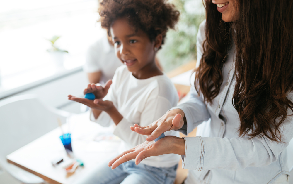 Young woman and kid playing with colorful clay molding different shapes