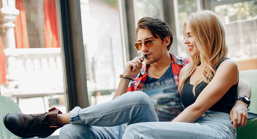 Stylish young couple with weed vape in a cafe