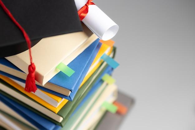 Free photo high angle of stacked books, a graduation cap and a diploma for education day