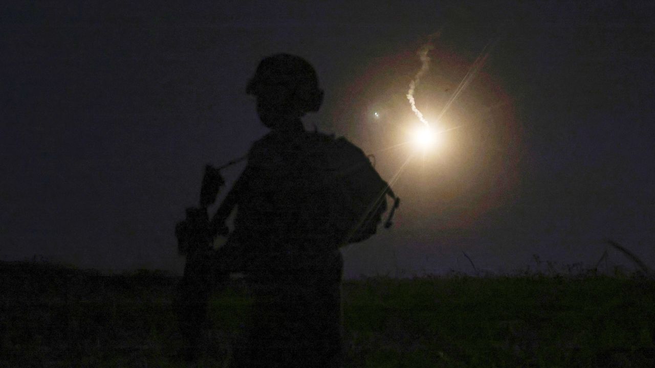 The silhouette of an Israeli soldier is outlined in the sky by a flare fired to search for a rocket that landed near Kibbutz Meitsar in the Golan Heights on April 9, 2023.