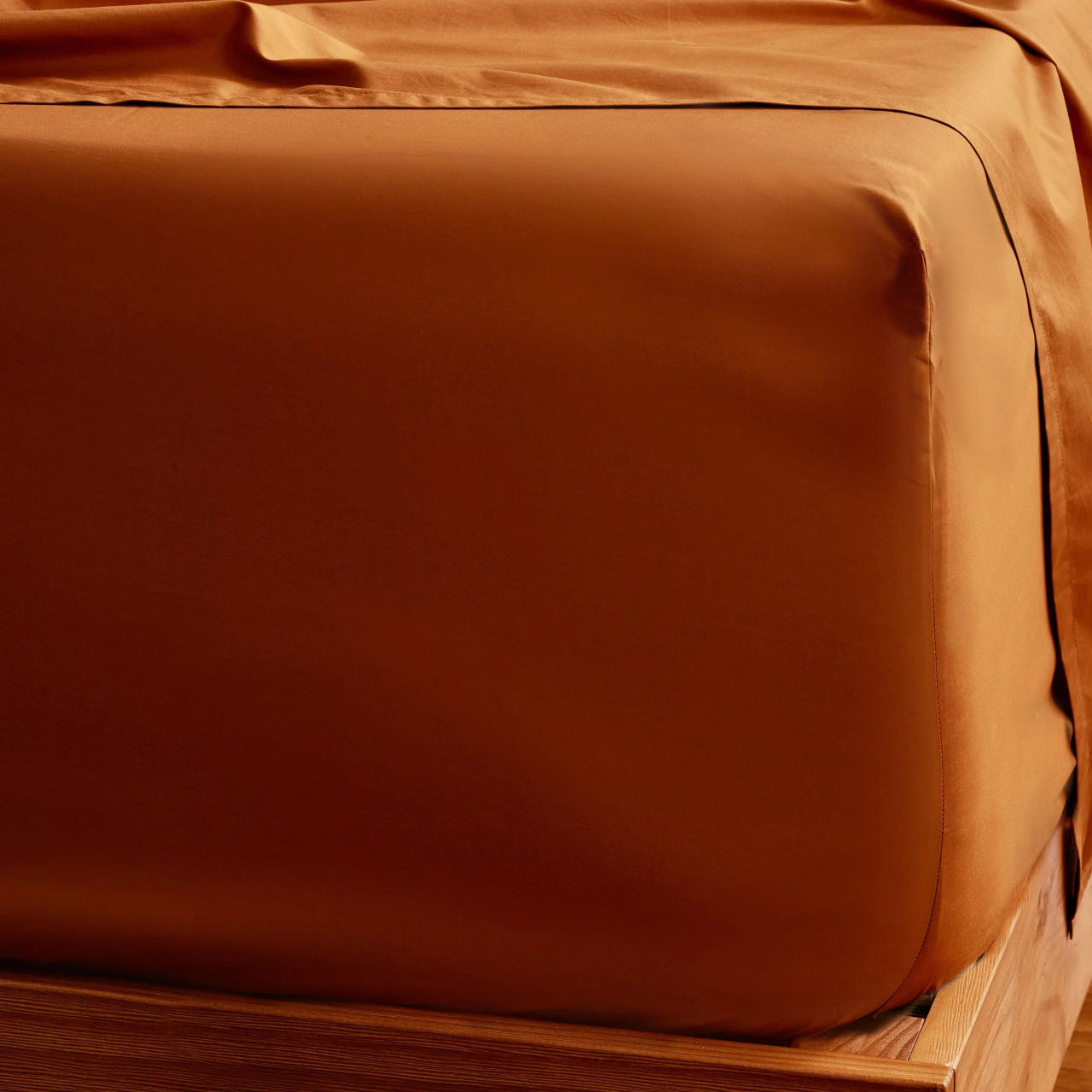 Corner of a bed with orange sheets