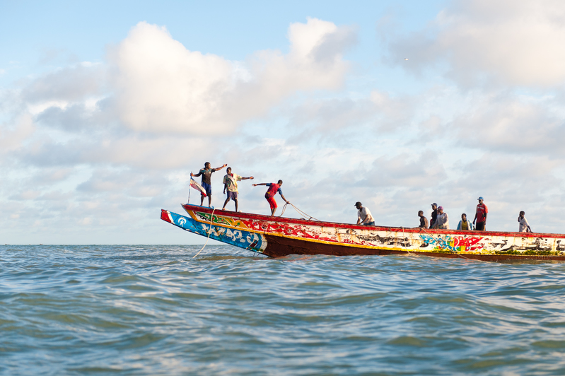 Ryhmä paikallisia kalastajia nostaa verkkoja kahteen kalastusveneeseen Afrikan länsirannikolla.