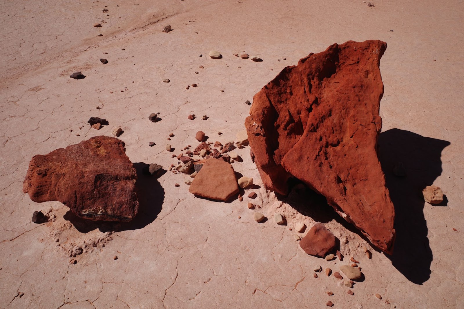 A imagem mostra duas grandes pedras de argila, de coloração marrom avermelhada, sobre uma superfície seca e desértica.