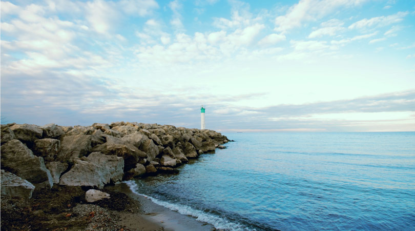 A white and blue lighthouse on a Lake Ontario beach in Fifty Point Conservation Area in Ontario, Canada.
