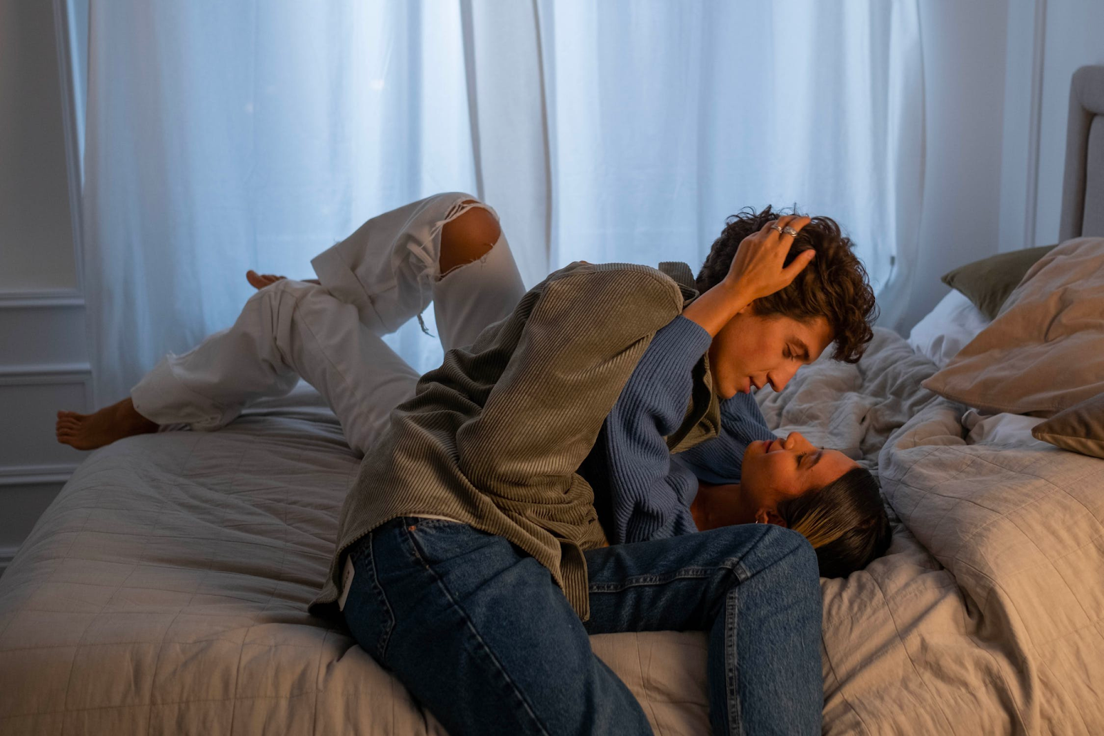 A couple laying down in bed looking at each other passionately
