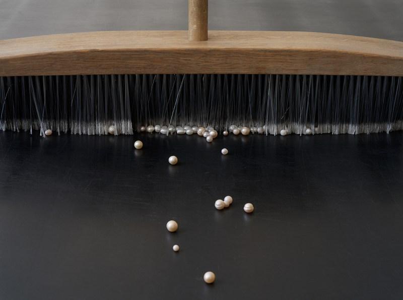 Nina Canell: Mother of Dust, 2023, pearls, broom, modified conveyer belt, 275 5/8 by 41 3/8 by 41 3/4 inches.