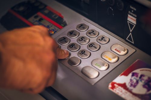 Person withdrawing money from an ATM with a debit card. 