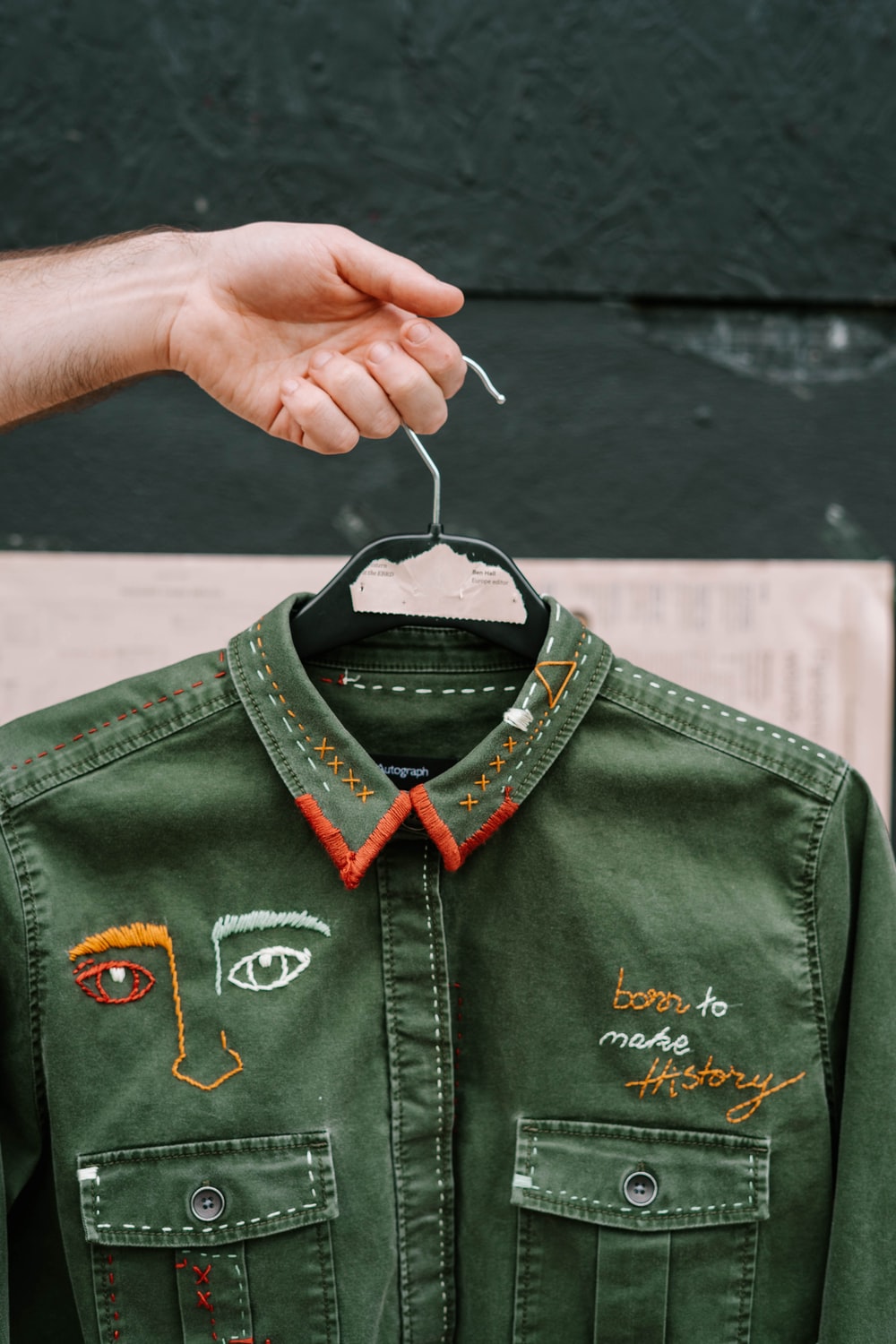 person holding upcycled green jacket with embroidery