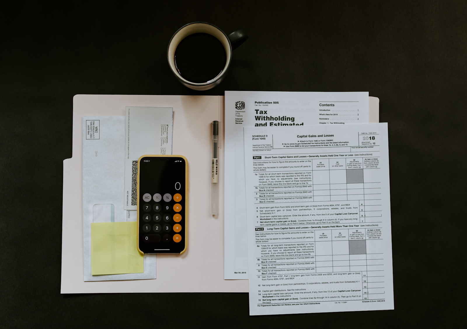 Financial Tax forms and a phone calculator organized atop a desk