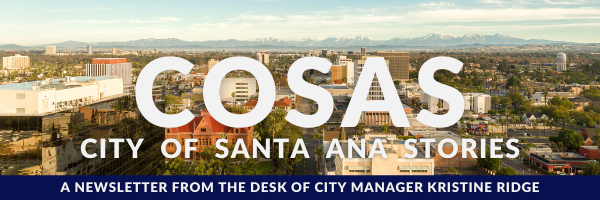An aerial image of the Santa Ana Civic Center, focusing around the old court house, with white text over laid, reading: COSAS CITY OF SANTA ANA STORIES. There is a blue bar at the bottom with white text which reads, "A NEWSLETTER FROM THE DESK OF CITY MANAGER KRISTINE RIDGE"