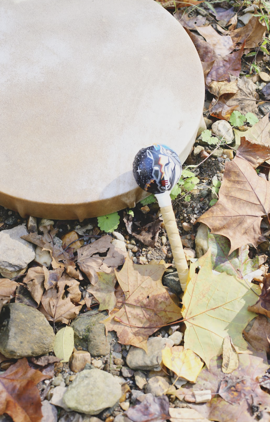 Drum and mallet used in shamanism rituals on a pile of leaves
