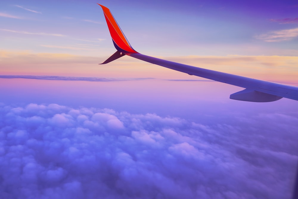 person in a plane flying at high altitude taking photo of left airplane wing during daytime