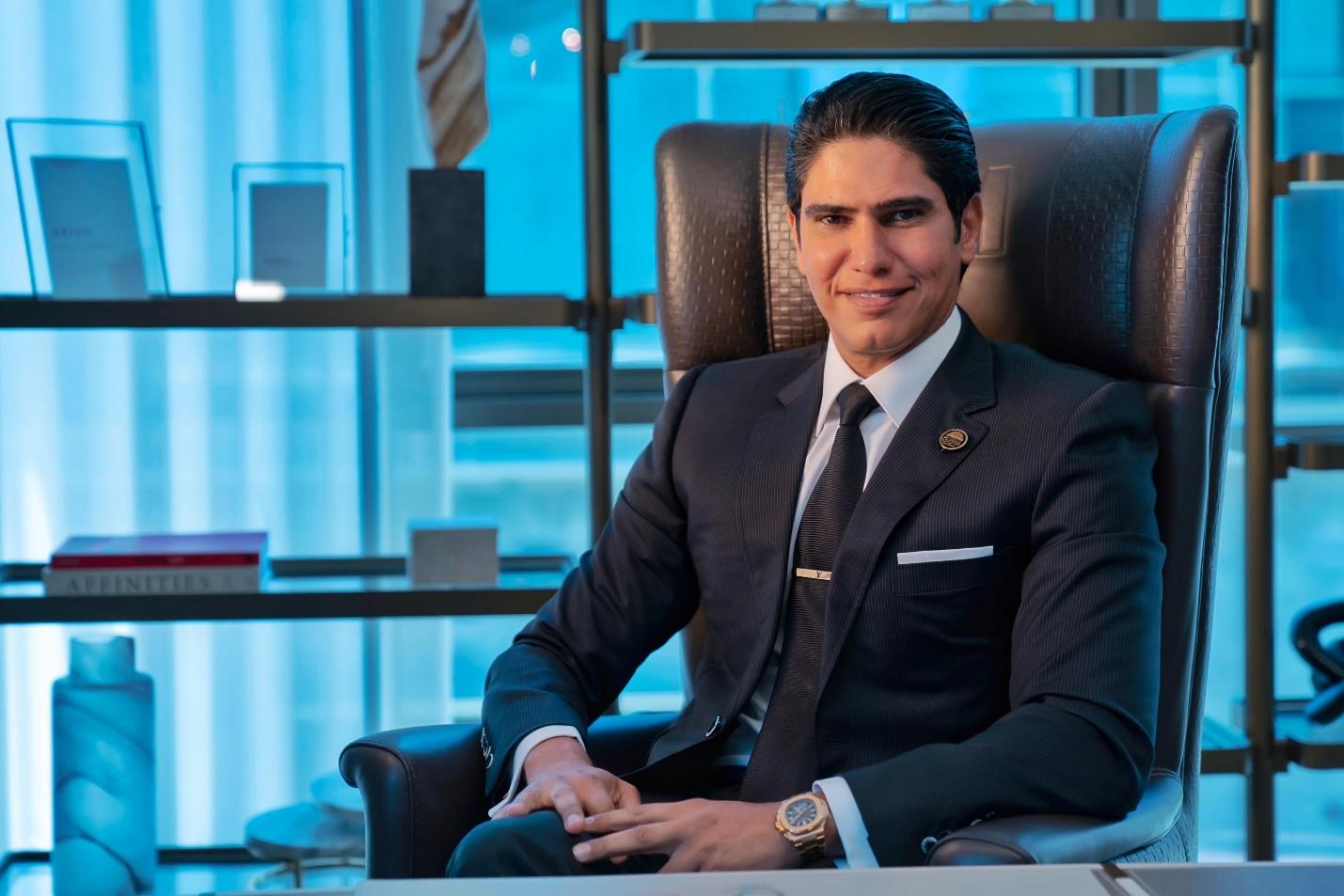 A person in a suit sitting in a chair

Description automatically generated