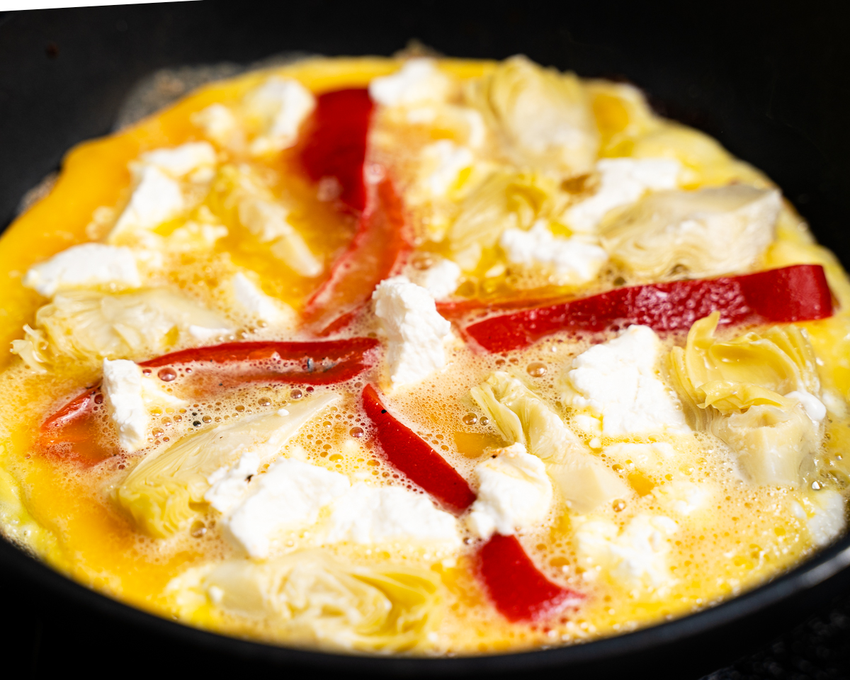 cooked omelette topped with red pepper, artichokes and goat cheese