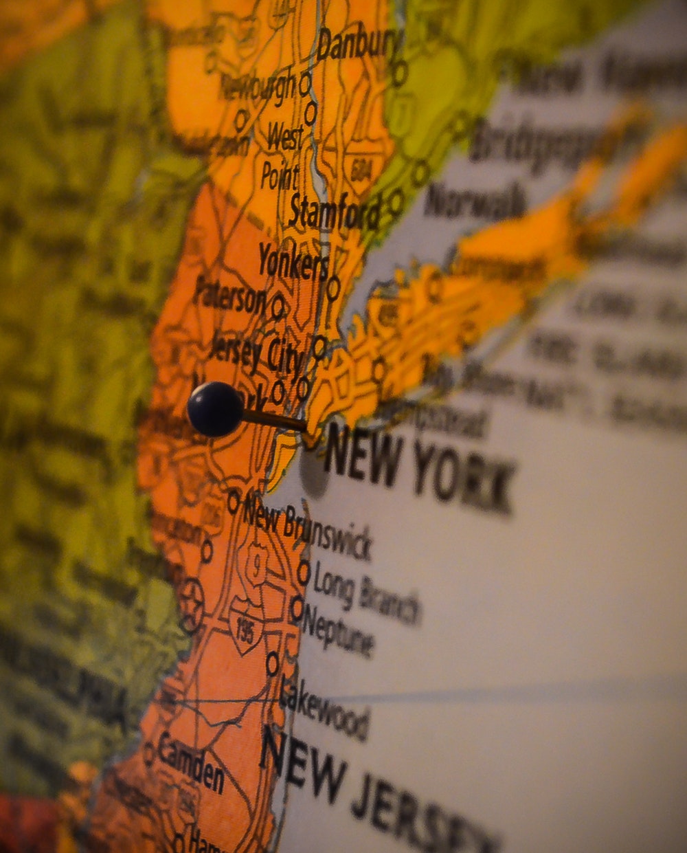 A close-up of a map with a pin stuck into it at the area of New York