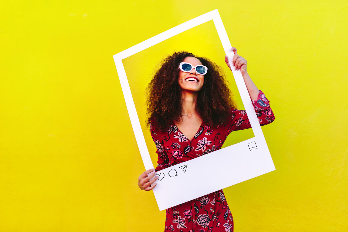 Social media campaign ideas: happy woman holding a cardboard cutout of an Instagram post