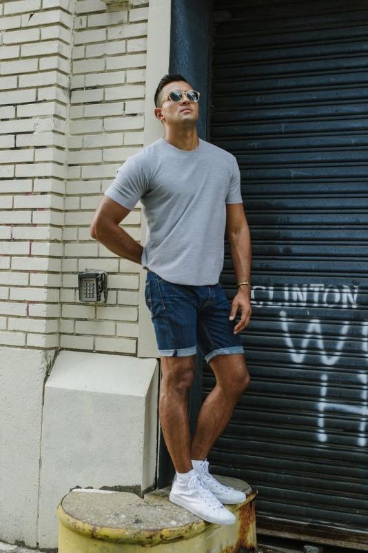 men styling denim blue shorts with a solid grey t-shirt with white sneakers