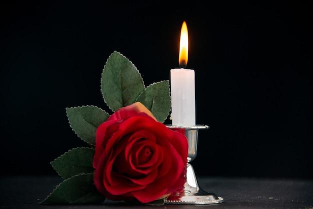 Vela acesa com flor vermelha como memória na superfície escura, assistência funeral