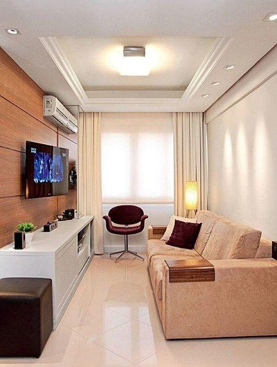 Sala com piso porcelanato branco, sofá em tom neutro, rack branca de madeira e painel de TV amadeirado