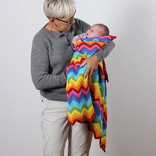 grandma holding baby wrapped in rainbow chevron knitted blanket
