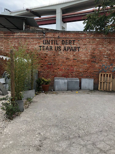 a photo of a brick wall that say 'until debt tear us apart'. 
