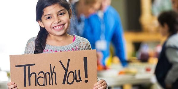 Young girl holding a cardboard sign that says thank you!