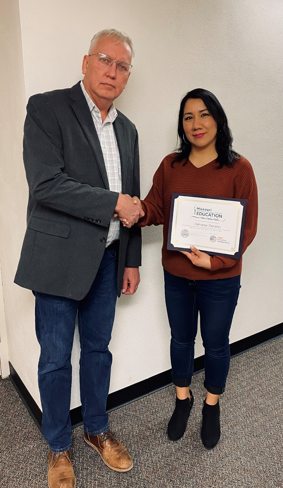 Andy Jett and Adriana Puentes holding a certificate and shaking hands