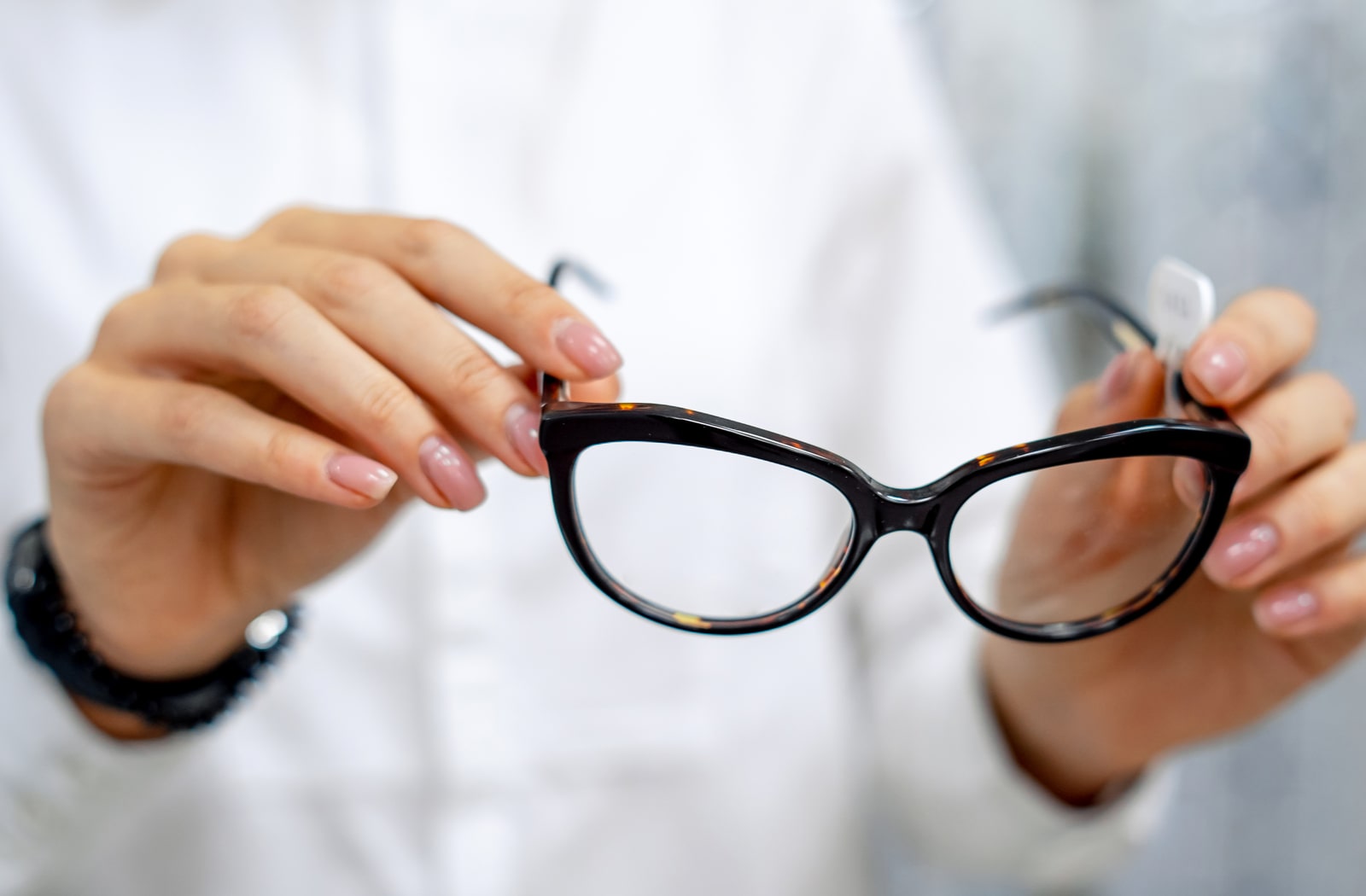 A female optician holding a pair of glasses with corrective lenses.