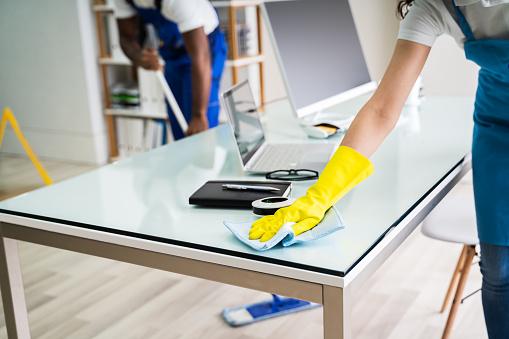 WeServe, a team of professionals cleaning the office area with a mop while removing dust from desk