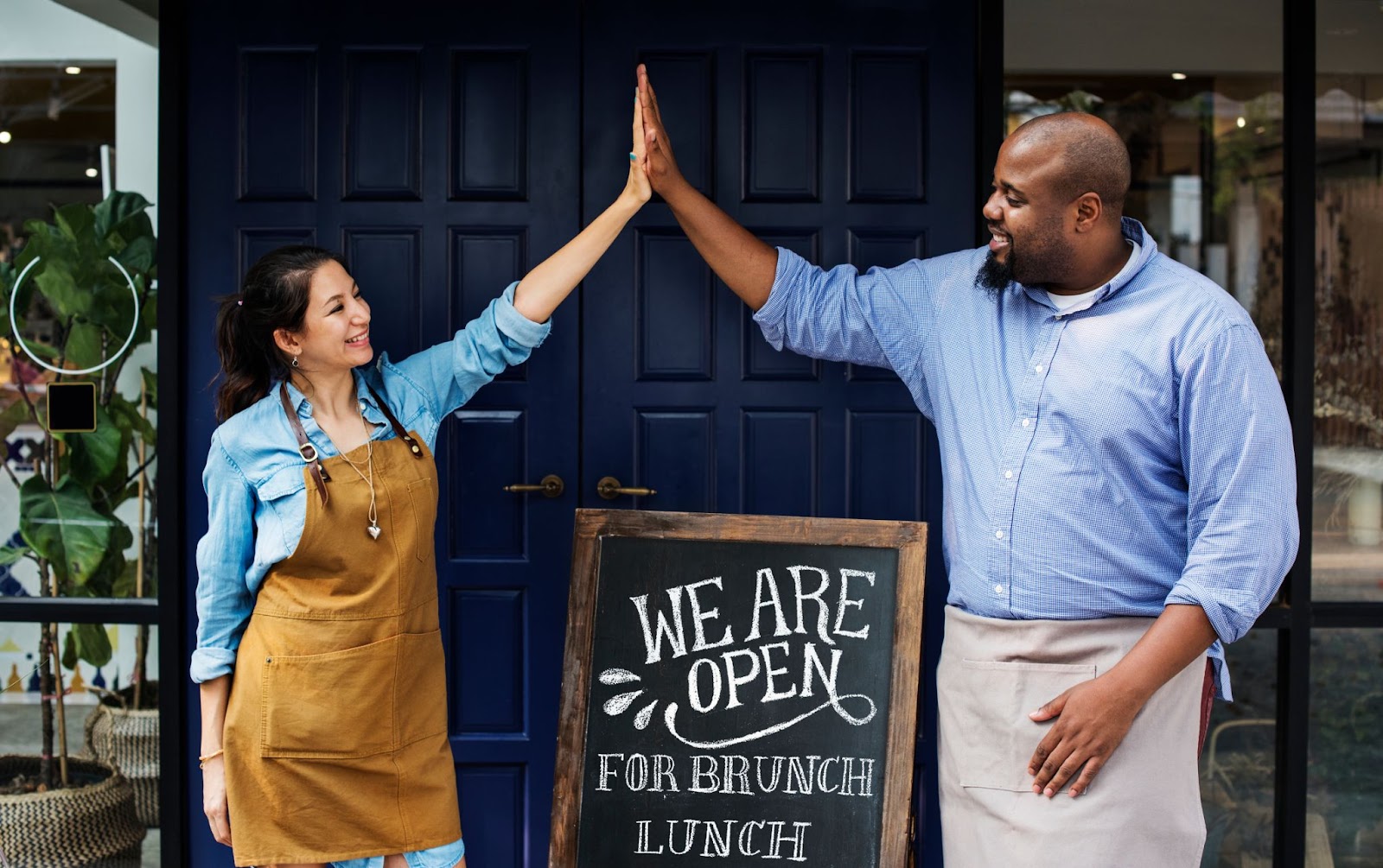 Two people high-fiving each other in front of a restaurant