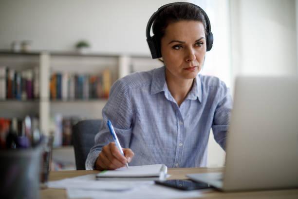 Mature woman working from home during COVID-19 pandemic Mature woman working from home during COVID-19 pandemic online learning stock pictures, royalty-free photos & images