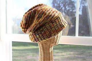 Speckled slouchy hat with a ribbed brim folded up modeled on a wicker head form in front of a window.