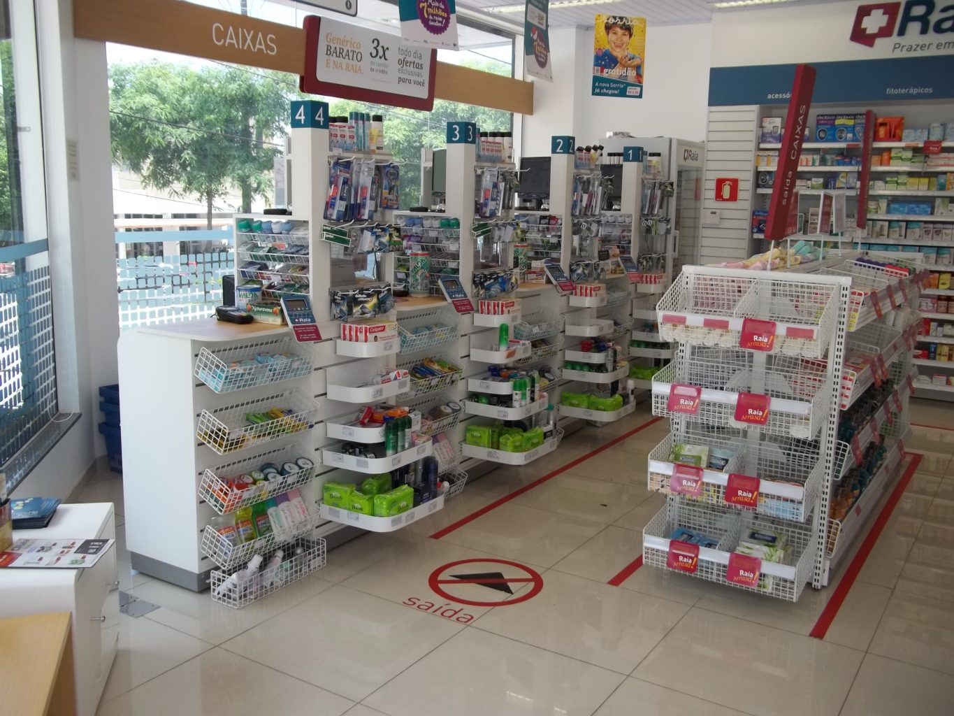 A imagem mostra o layout ideal para o checkout de farmácia, com uma prateleira delimitando o corredor de caixas próximos à saída.