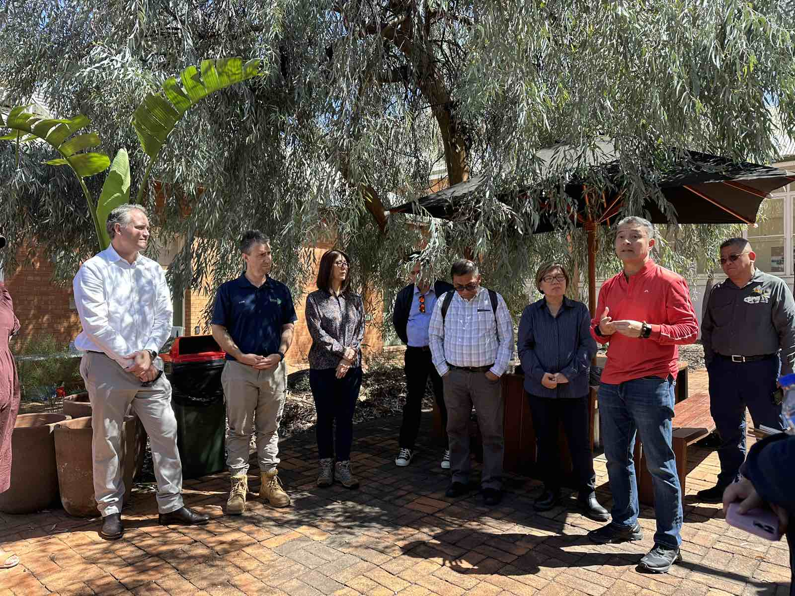 A group of people standing under a treeDescription automatically generated