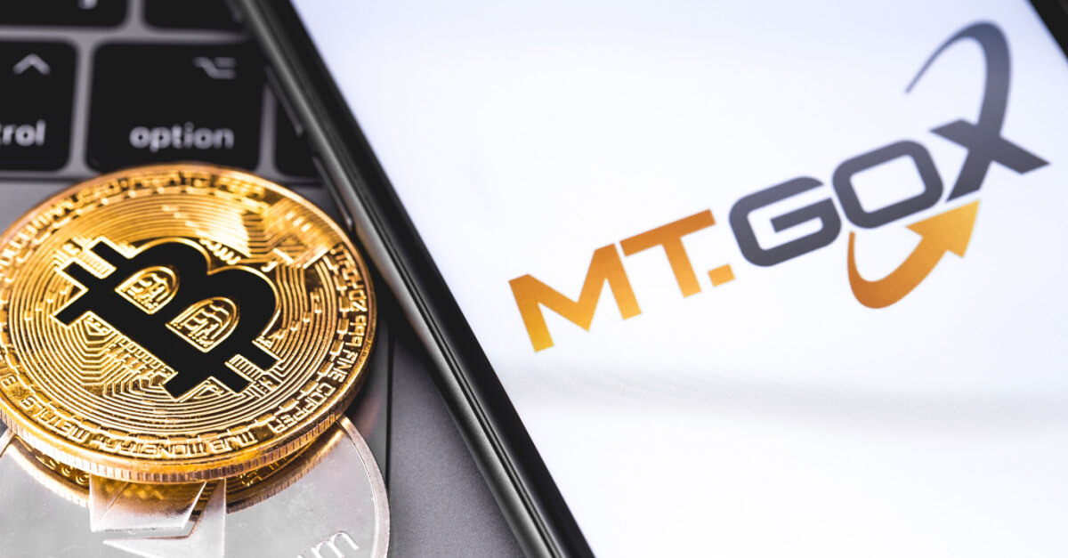 Gold bitcoin on keyboard besides MT Gox logo on mobile display