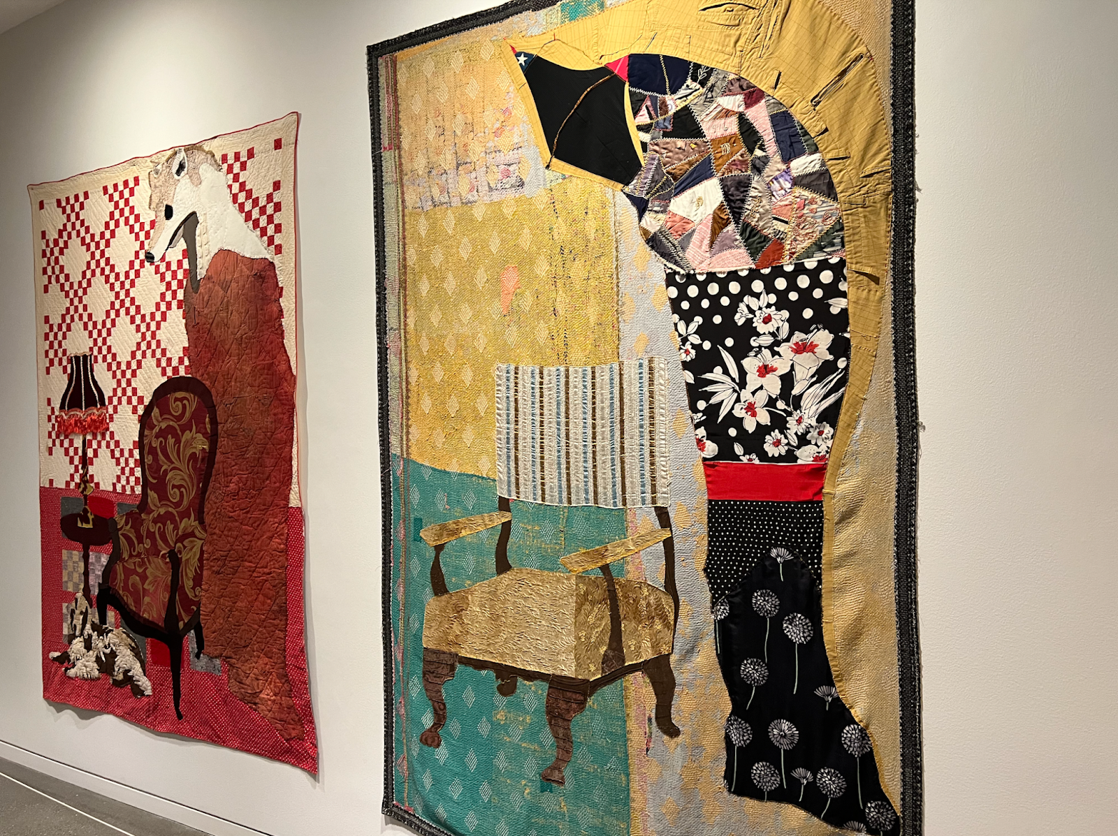 Two art pieces made of clothing side by side. The first art piece is a sofa chair next to a lamp and a wolf like figure. The second art piece is a gold chair and a black floral figure next to it.