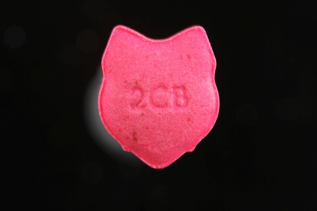 Foto colorida de uma  pílula de 2C-B em fundo preto