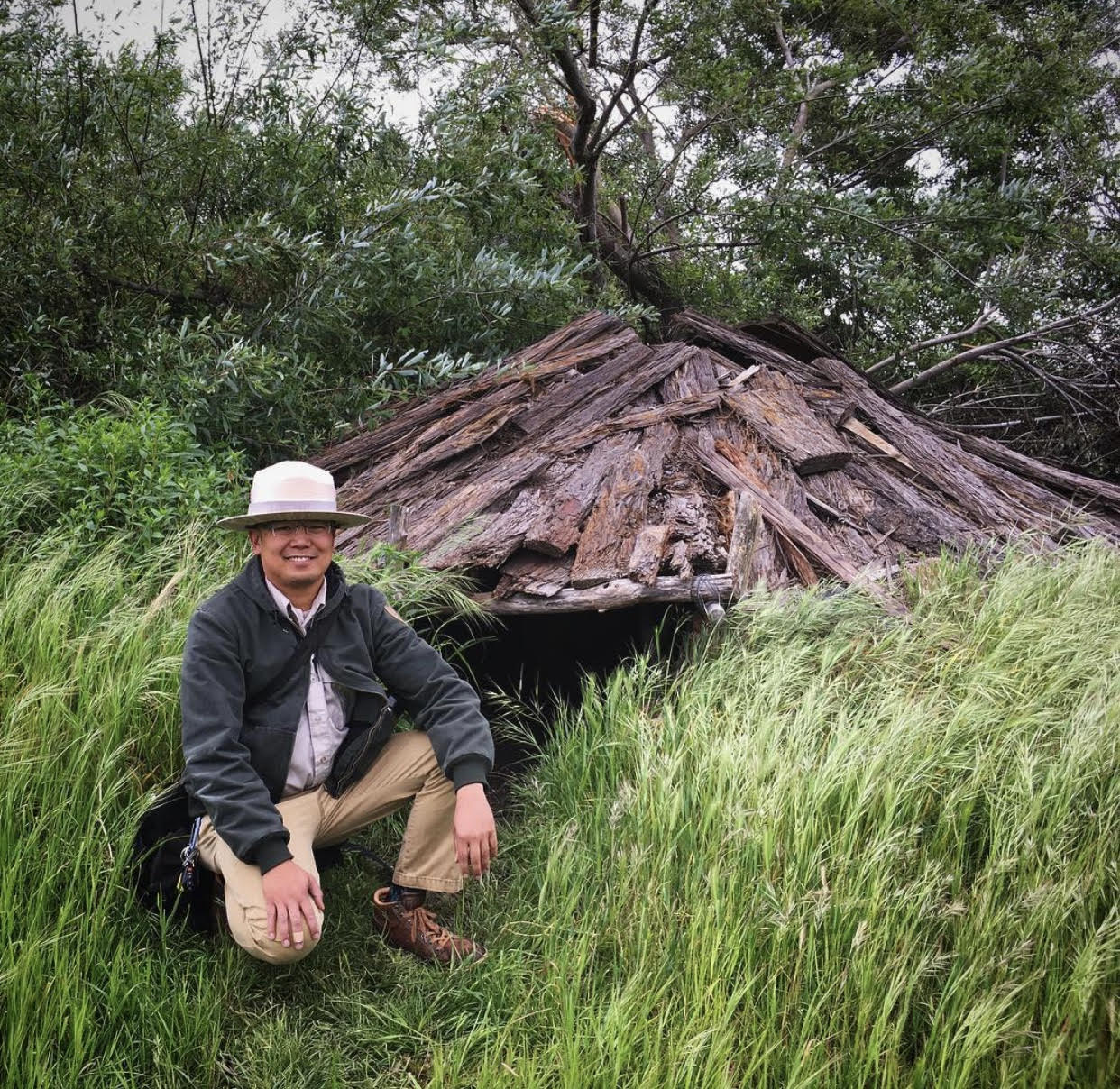 Naturalist Francis Mendoza in front of a re-created sweathouse with a redwood bark roof, in Tuibun or present-day Fremont on Chochenyo land.