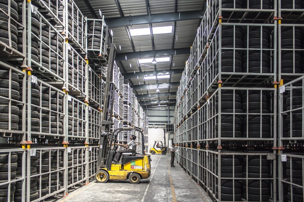 A forklift lifts a pallet high to use vertical space.