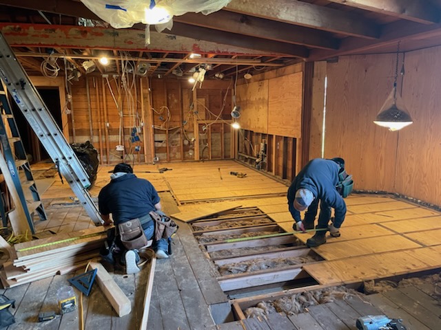 two employees measuring the floor during a custom home build