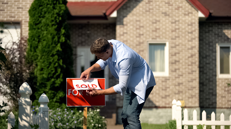 FSBO home seller putting "sold" sign over his for sale sign after a successful sale at the right price