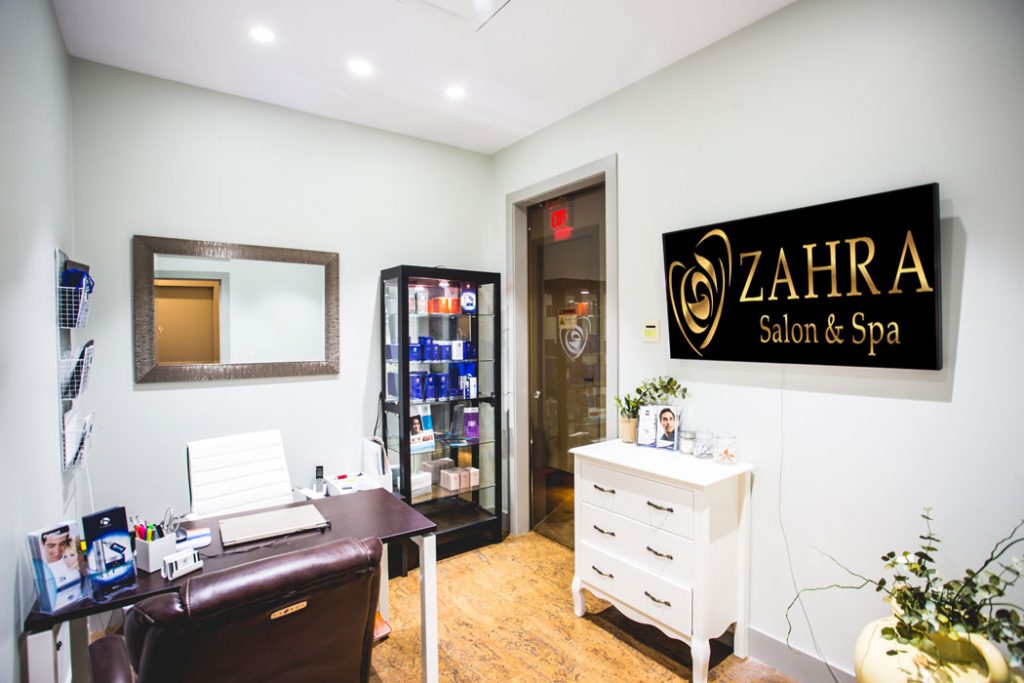 the interior reception area of Zahra Salon and Spa, with a desk and a display case of self-care hair products