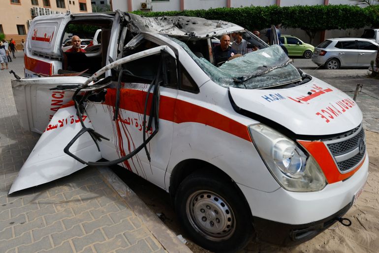Palestinians inspect an ambulance hit by an Israeli strike, after Hamas gunmen launched a surprise attack against Israel